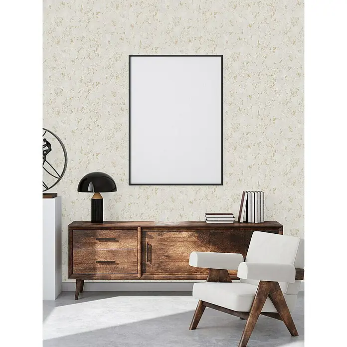 A.S. Création Casual Living Vliestapete Struktur - Grau/Gold/Metallic, Uni, 10,05 x 0,53 m - Einrichtungsgegenstände wie ein Holzschrank, eine Lampe, Bücher und ein Sessel schaffen eine gemütliche Atmosphäre in einem modernen Raum.