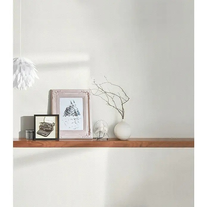 A.S. Création Casual Living Vliestapete - Wollweiß, Uni, 10,05 x 0,53 m - Nahaufnahme eines Holzregals mit dekorativen Gegenständen wie einem Bilderrahmen, einer Vase und einer kleinen Lampe.