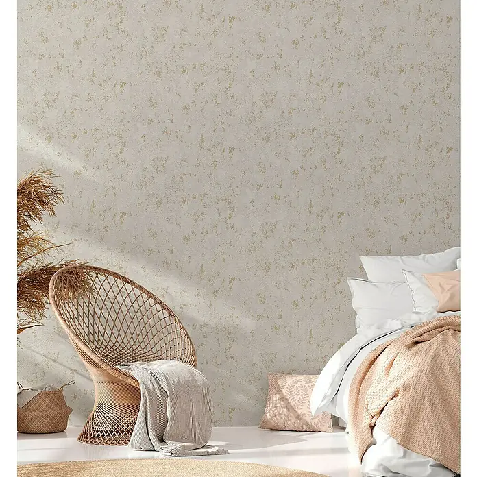 A.S. Création Casual Living Vliestapete Struktur - Grau/Gold/Metallic, Uni, 10,05 x 0,53 m - Heller Raum mit Rattan-Stuhl und Bett. Die strukturierte Wand sorgt für eine gemütliche Atmosphäre.