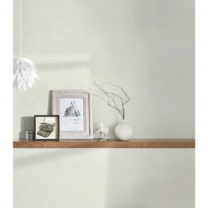 A.S. Création Casual Living Vliestapete - Freundliches Weiß, Uni, 10,05 x 0,53 m - Dekorative Innenaufnahme mit Bilderrahmen, Vase und Tischventilator auf einem Regal, die eine gemütliche und stilvolle Atmosphäre erzeugen.