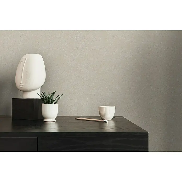 A.S. Création Casual Living Vliestapete - Grau/Beige, Uni, 10,05 x 0,53 m - Nahaufnahme von einer weißen Kopf-Skulptur, einer kleinen Pflanze und einem Bleistift auf einem dunklen Holzschreibtisch.