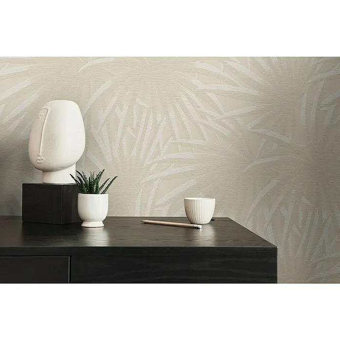 A.S. Création Casual Living Vliestapete Palmenblätter - Beige/Weiß, Floral, 10,05 x 0,53 m - Nahaufnahme von Dekorationsartikeln auf einem schwarzen Tisch vor einer Wand mit dezentem Blätterdesign.