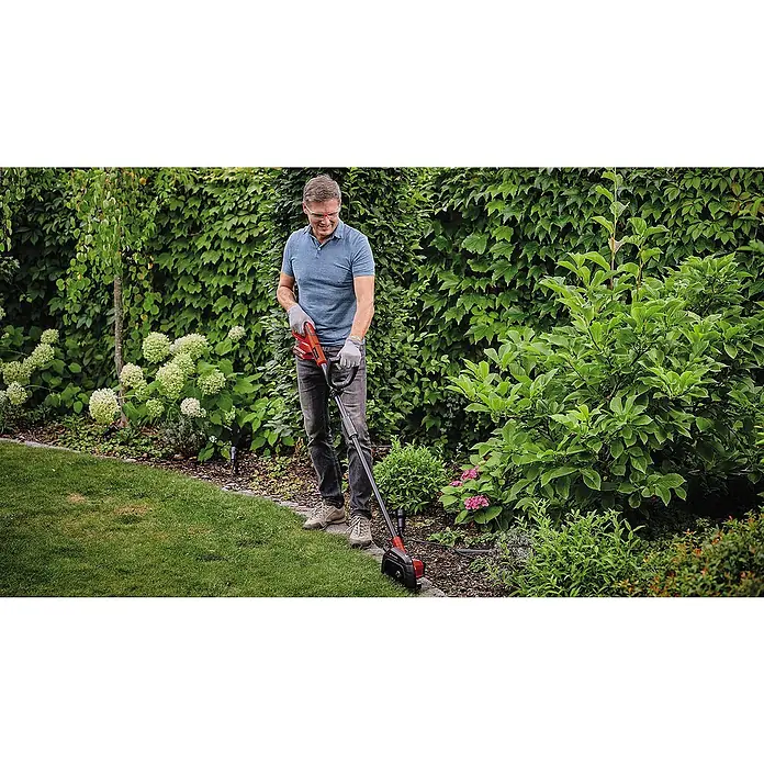 Einhell Power X-Change 18V Rasenkantenschneider GE-LE 18/190 LI - Ohne Akku, 18 V - Ein Mann benutzt einen Rasentrimmer im Garten. Der Rasentrimmer ist rot und schwarz und hat einen langen Griff.