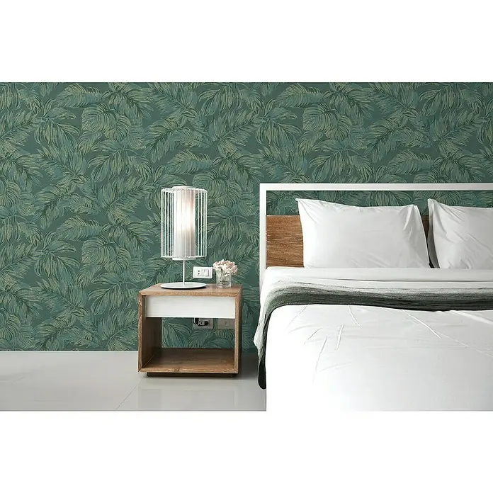 A.S. Création Casual Living Vliestapete - Grün/Gold, Floral, 10,05 x 0,53 m - Ein Schlafzimmer mit einem Nachttisch und einer Lampe, alles vor einer grünen Blättertapete.