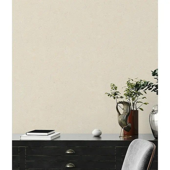 A.S. Création Casual Living Vliestapete Struktur - Beige, Uni, 10,05 x 0,53 m - Nahaufnahme eines eleganten, dunklen Konsolentisches mit dekorativen Objekten wie Büchern, einer Pflanze und einer Skulptur.