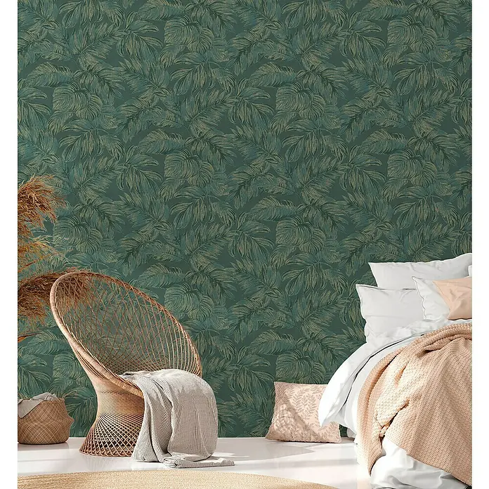 A.S. Création Casual Living Vliestapete - Grün/Gold, Floral, 10,05 x 0,53 m - Zimmer mit einer Wandtapete mit grünen Blättern, einem Rattansessel und einem Bett.