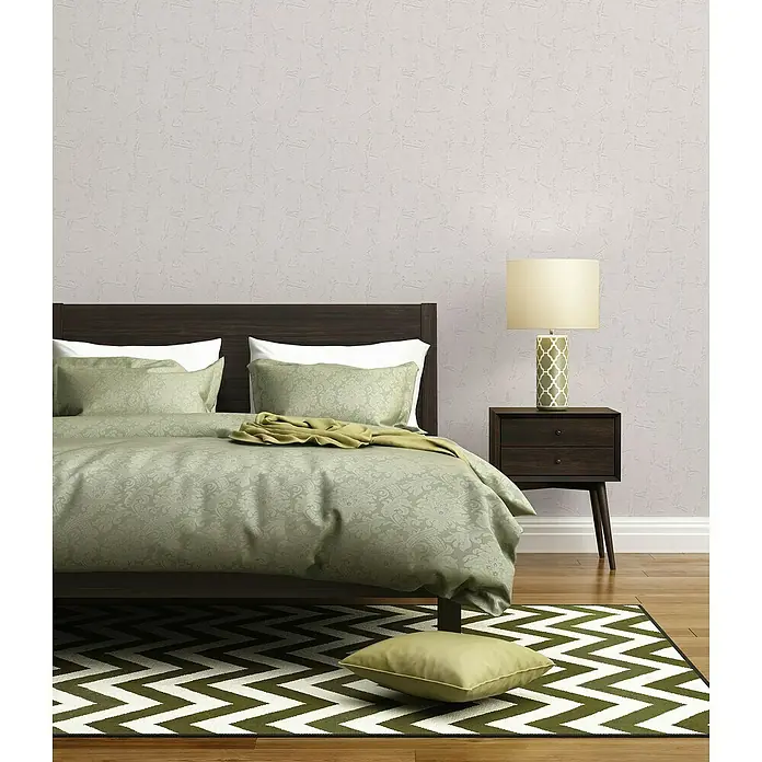 A.S. Création Casual Living Vliestapete Strukturtapete - Weiß, Uni, 10,05 x 0,53 m - Schlafzimmer-Interieur mit dunkelbraunem Bett, grünem Bettzeug, Nachttischlampe und Zickzack-Teppich für eine stilvolle und einladende Atmosphäre.