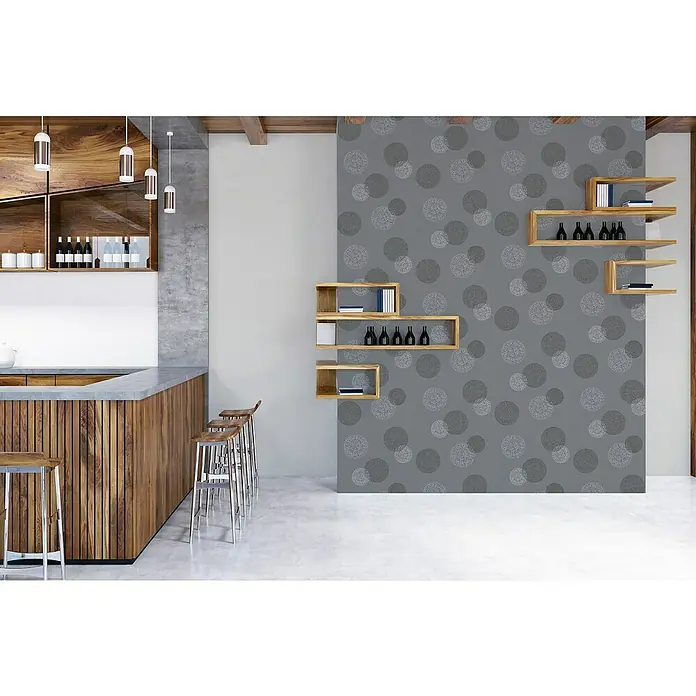 A.S. Création Casual Living Vliestapete Kreise - Anthrazitgrau, Grafisch, 10,05 x 0,53 m - Eine moderne Bar mit Holzakzenten, grauer Arbeitsplatte und stilvollen Hockern. Akzentwand mit Kreismuster und Holzregalen.