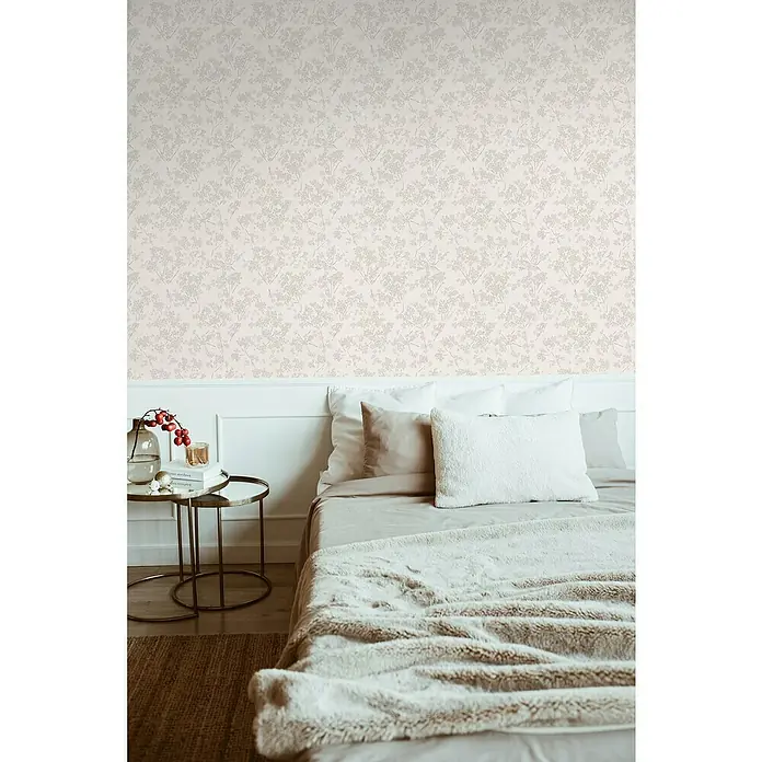 A.S. Création Casual Living Vliestapete Blümchen - Weiß/Grau, Floral, 10,05 x 0,53 m - Nahaufnahme eines eleganten Schlafzimmers mit blumiger Tapete, einem weichen Bett und einem goldenen Beistelltisch.