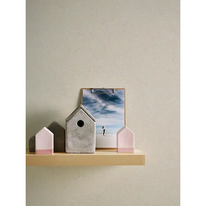 A.S. Création Casual Living Vliestapete Struktur - Beige, Uni, 10,05 x 0,53 m - Dekorative Hausobjekte aus Beton und rosa Akzenten auf einem hellen Holzregal vor einer schlichten Wand. Ein Clipboard mit Strandmotiv lehnt dahinter.