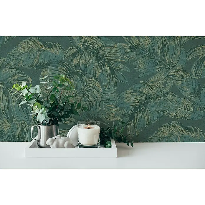 A.S. Création Casual Living Vliestapete - Grün/Gold, Floral, 10,05 x 0,53 m - Nahaufnahme eines weißen Tabletts mit Kerze, dekorativem Hasen und Eukalyptus vor einer grünen Blättertapete.
