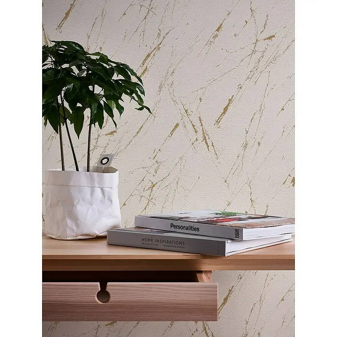 A.S. Création Casual Living Vliestapete Marmor - Beige/Gold/Metallic, Steinoptik, 10,05 x 0,53 m - Nahaufnahme eines stilvollen Holzschreibtischs mit Pflanze und Büchern, der ein modernes, elegantes Ambiente vermittelt.