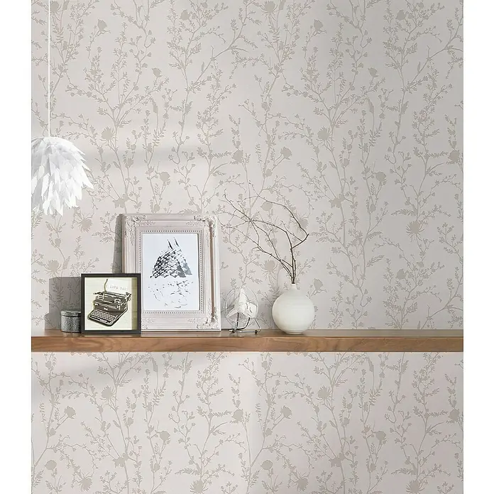A.S. Création Casual Living Vliestapete - Hellrosa/Hellgrau, Floral, 10,05 x 0,53 m - Ein elegantes Zimmer mit einer hellen Blumentapete, einem Holzregal, Bildern und Dekorationsgegenständen, das eine ruhige und stilvolle Atmosphäre schafft.