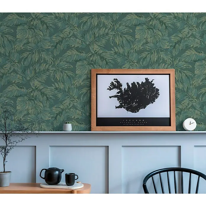 A.S. Création Casual Living Vliestapete - Grün/Gold, Floral, 10,05 x 0,53 m - Zimmerdekor mit einer Iceland-Wandkarte im Holzrahmen, die auf einem Regal mit Pflanzen und einer Teekanne steht, vor einer grünen Blättertapete.