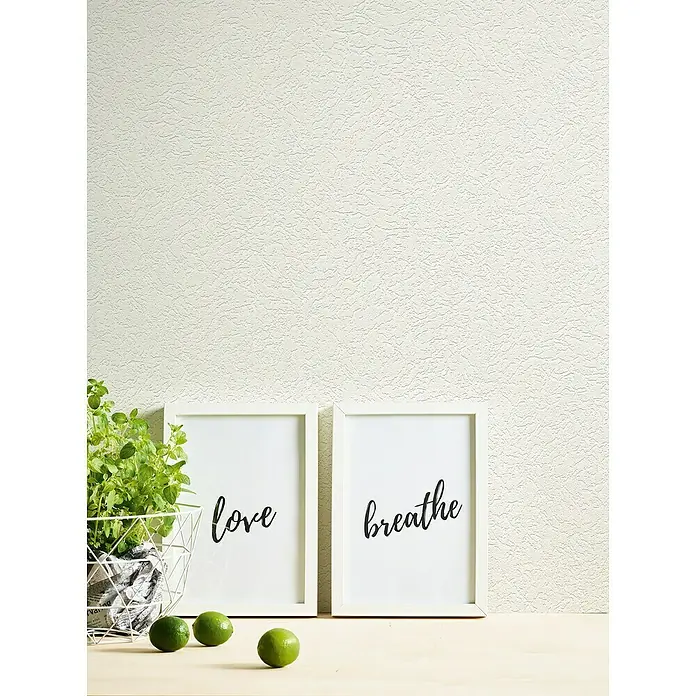 A.S. Création Casual Living Vliestapete Putzeffekt - Weiß, Uni, 10,05 x 0,53 m - Wanddekoration mit den Wörtern "Liebe" und "Atmen" in weißen Rahmen, begleitet von einer Pflanze und Limetten.