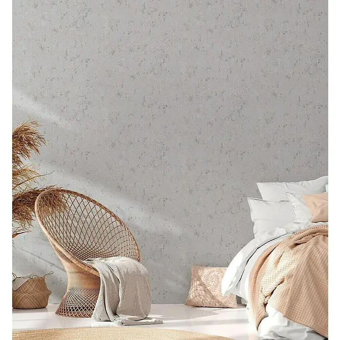 A.S. Création Casual Living Vliestapete Struktur - Grau/Silber/Metallic, Uni, 10,05 x 0,53 m - Nahaufnahme eines Korbstuhls mit Decke und Bett mit rosa Überwurf, die eine gemütliche und entspannende Atmosphäre schaffen.