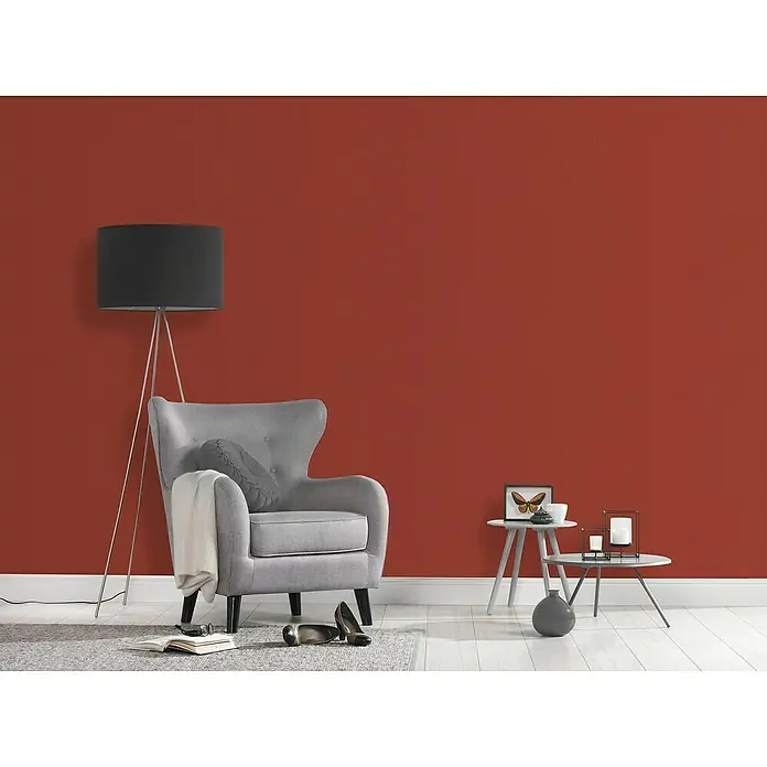 A.S. Création Casual Living Vliestapete - Rot, Uni, 10,05 x 0,53 m - Wohnzimmer mit grauem Sessel, Stehlampe und Beistelltischen vor einer roten Wand. Gemütliche Atmosphäre mit stilvollem Interieur für entspannte Stunden.