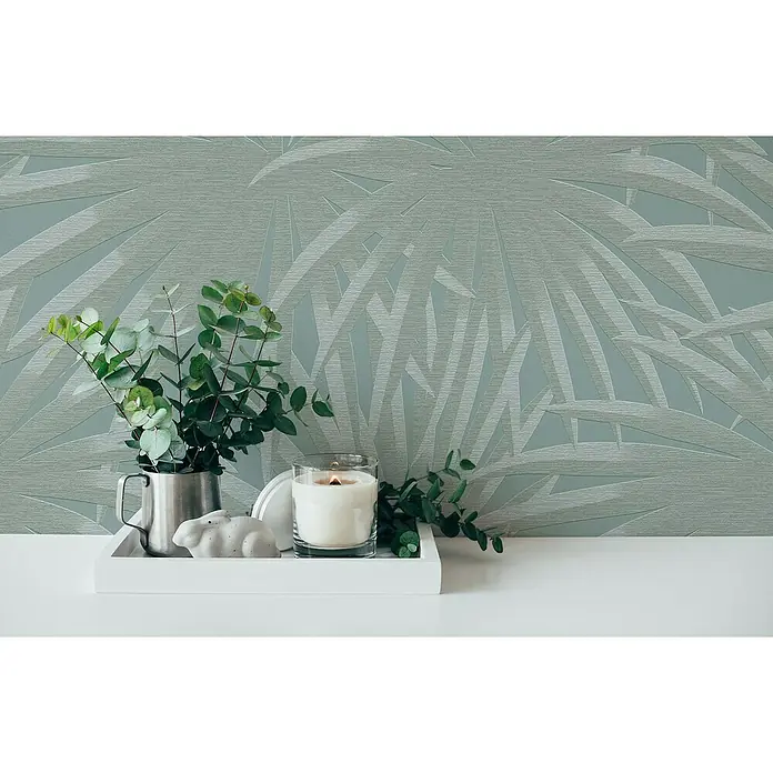 A.S. Création Casual Living Vliestapete Palmenblätter - Blau/Mint, Floral, 10,05 x 0,53 m - Stillleben mit Kerze, Grünpflanzen und Dekoration auf einem weißen Tablett vor einer blaugrauen Tapete mit Blattmuster.