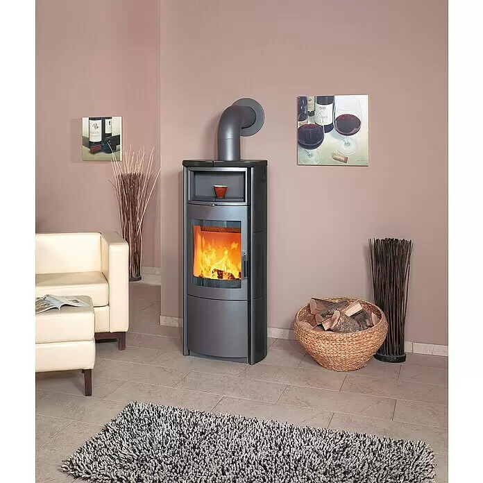Hark Kaminofen Nika ECOplus - 7 kW, Raumheizvermögen: 193 m³, Material Verkleidung: Keramik, Schwarz - Moderner, dunkelgrauer Holzofen mit sichtbarem Feuer und geschwungenem Rauchrohr in einem Wohnzimmer.