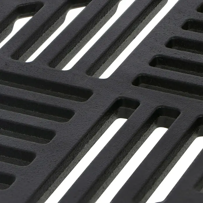 ACO Self Gussrost - 25 x 25 x 0,7 cm - Nahaufnahme eines gusseisernen Grillrosts mit einem diagonalen Muster und dunklen, rechteckigen Schlitzen.