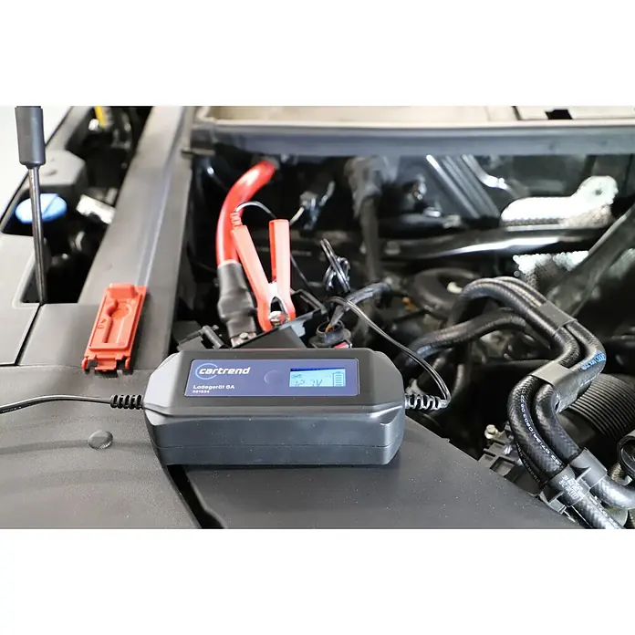 Cartrend Automatik-Ladegerät DP6.1Ladestrom: 6 A - Ein Cartrend Ladegerät 6A lädt eine Autobatterie. Das Display zeigt 12.7V an, während rote Klemmen an den Batteriepolen befestigt sind.