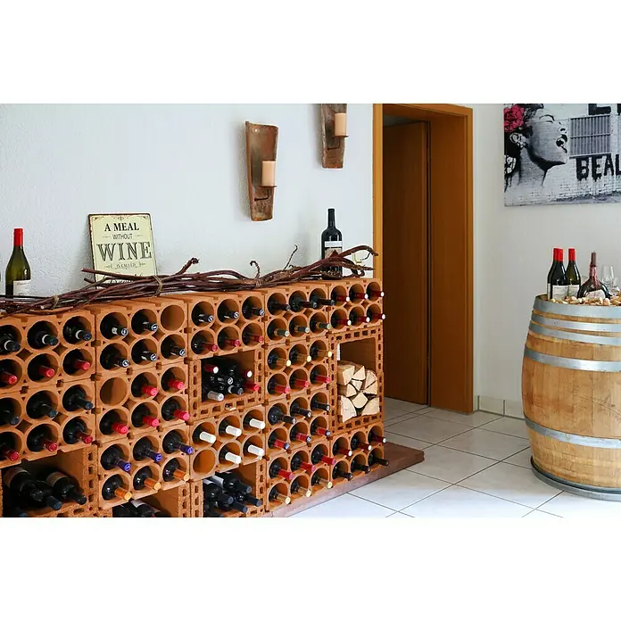 Weinregal - 36,5 x 24 x 24,9 cm, Anzahl Flaschen: 6 Stk., Ton - Ein Weinkeller mit einem Regal aus Terrakotta-Ziegeln, gefüllt mit Weinflaschen, neben einem Holzfass-Tisch und Wanddeko, ideal für Weinliebhaber.