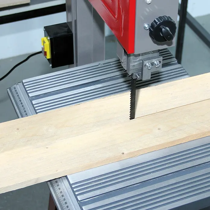 Einhell Hoja de sierra de cinta - L x An x Al: 1.710 x 6 x 0,65 mm - Primer plano de una sierra de cinta cortando una tabla de madera clara, destacando la hoja y el proceso de corte.