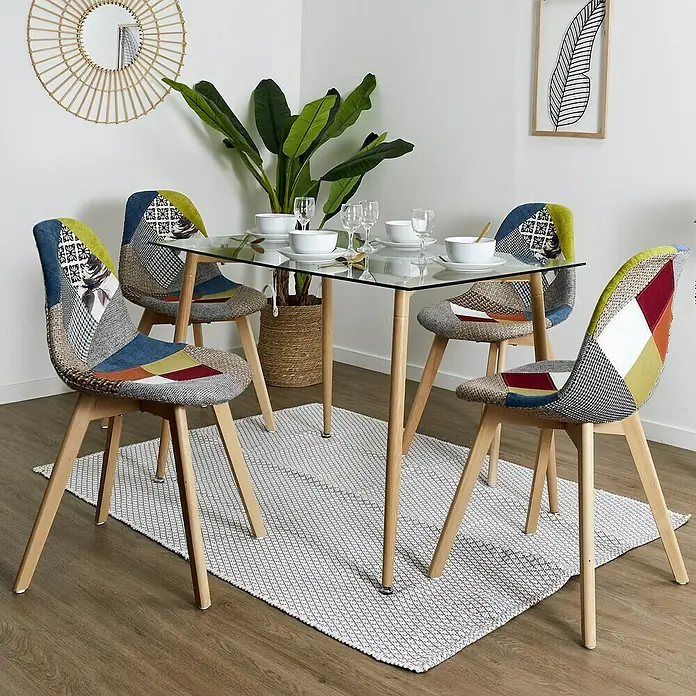 Home Deco Factory Silla Patchwork - Multicolor, 4 pzs. - Una mesa de comedor con tapa de cristal y cuatro sillas patchwork sobre una alfombra estampada en una habitación luminosa.