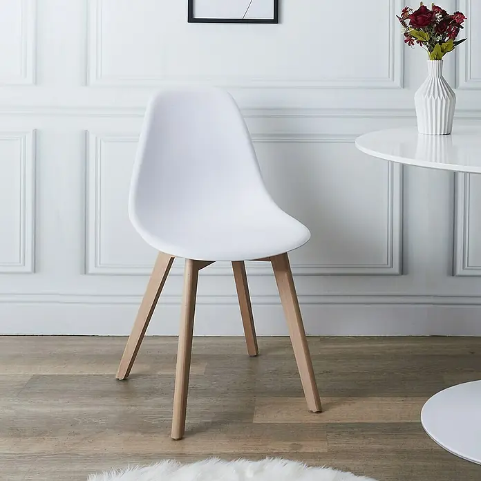 Home Deco Factory Silla Stockholm - Blanco, 4 pzs. - Primer plano de una silla blanca con patas de madera delante de una pared con paneles y una mesa redonda.