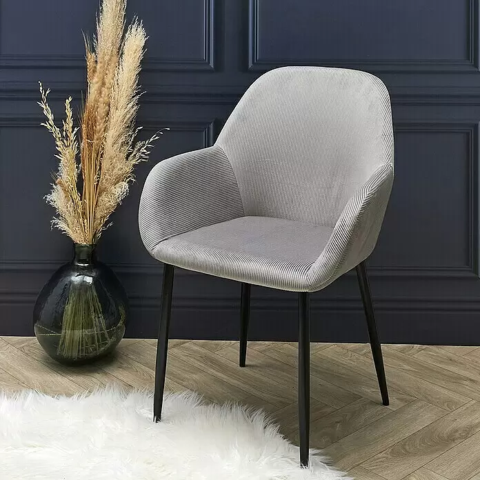 Home Deco Factory Silla butaca Giulia - Gris, 2 pzs. - Sillón de tela acanalada gris claro con patas negras sobre suelo de madera con alfombra blanca.