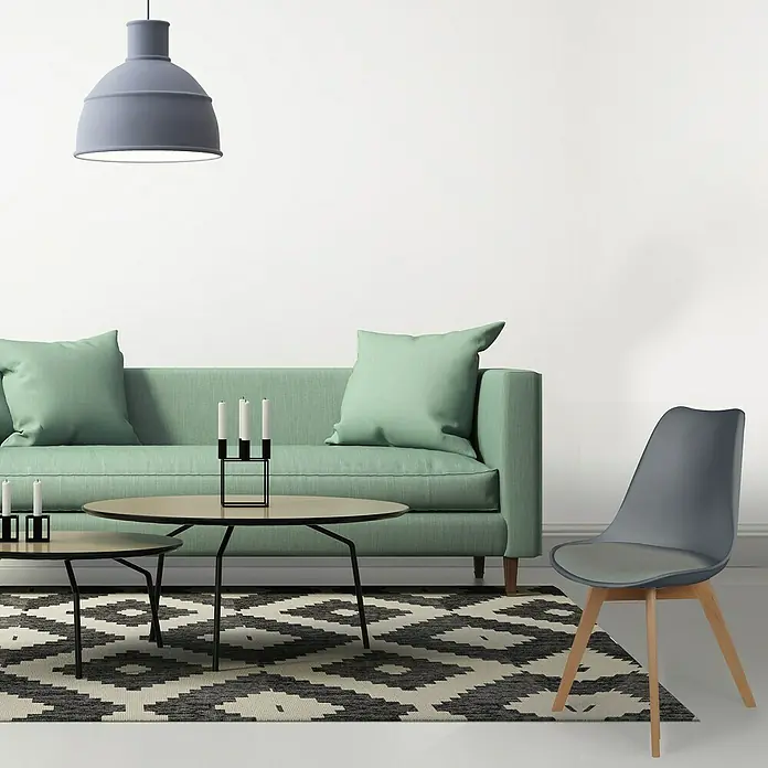 Home Deco Factory Silla Copenhague - Gris, 4 pzs. - Una silla gris con patas de madera en un salón moderno con sofá verde y alfombra. La silla es un complemento elegante.