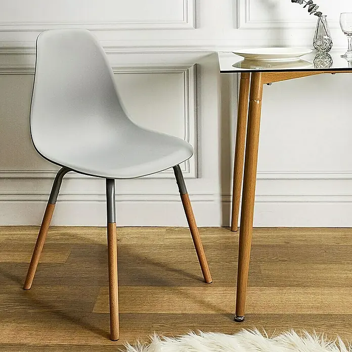 Home Deco Factory Silla Phenix - Gris, 4 pzs. - Primer plano de una silla moderna con patas de madera y asiento gris junto a una mesa de comedor con tapa de cristal.