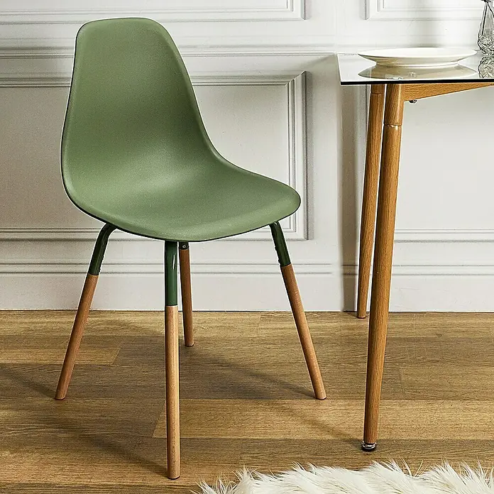 Silla Phenix - Verde, 4 pzs. - Una silla verde con patas de madera junto a una mesa de cristal en una habitación con paredes paneladas.