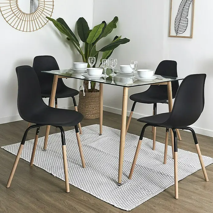 Silla Phenix - Negro, 4 pzs. - El moderno juego de comedor presenta una mesa con tapa de cristal con cuatro sillas negras con patas de madera y una alfombra.