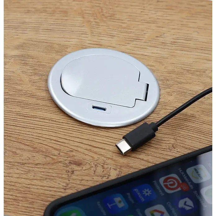 UniTEC Steckdose Tischsteckdose mit USB C - Schwarz, Silber, Kabellänge: 1,5 m - Nahaufnahme einer versenkbaren USB-C-Tischsteckdose auf einem Schreibtisch mit Ladekabel und Smartphone.