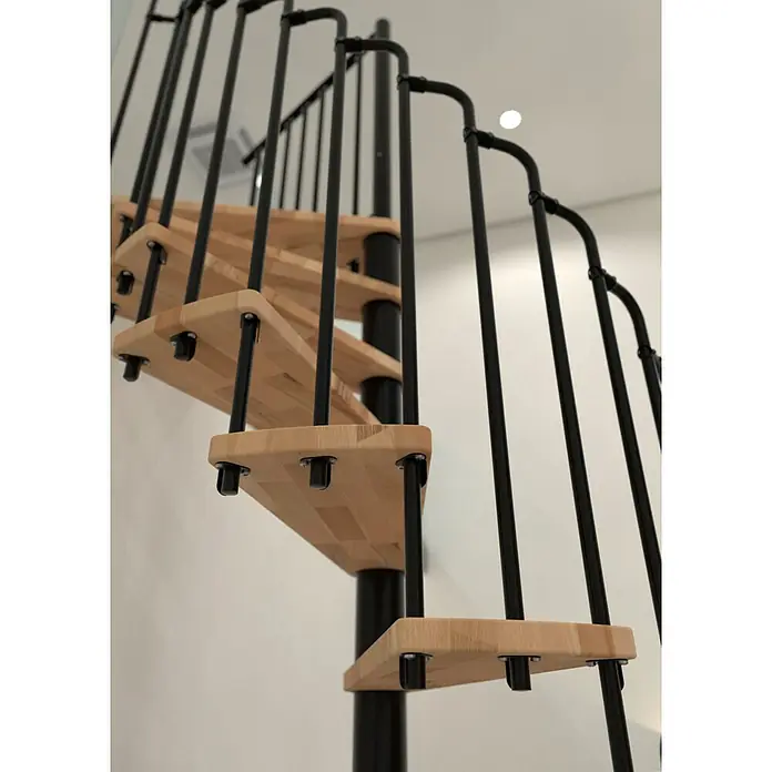 Minka Spindeltreppe Paris - Durchmesser: 140 cm, Schwarz, Farbe Stufen: Buche Natur, Geschosshöhe: 282 cm - Eine elegante Wendeltreppe aus hellem Holz mit schwarzen Metallgeländern fügt sich stilvoll in den Raum ein. Modernes Design trifft auf Funktionalität.