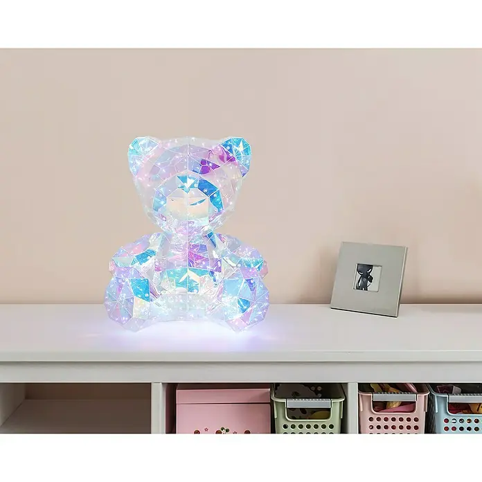 Tween Light LED-Dekoleuchte Benny - 6 W, Transparent/Irisierend, L x B x H: 28,5 x 32 x 40 cm, Benny - Ein holographischer Teddybär aus Acryl mit eingebauten Lichtern sitzt auf einem Regal.