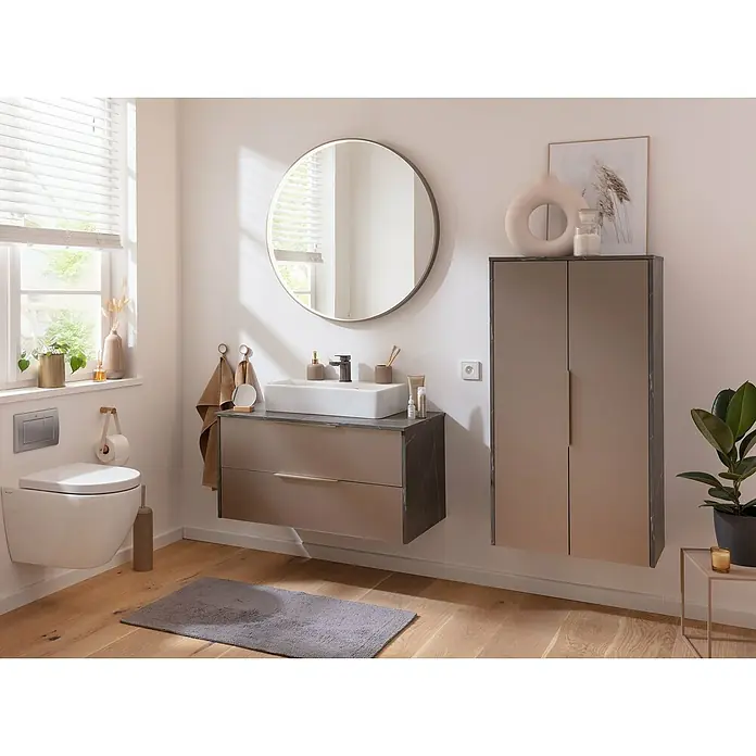 Camargue Lichtspiegel AluDurchmesser: 90 cm, Goldbronze - Ein Badezimmer mit hängendem WC, Waschtischunterschrank und einem Spiegelschrank. Der Raum ist hell und freundlich gestaltet.