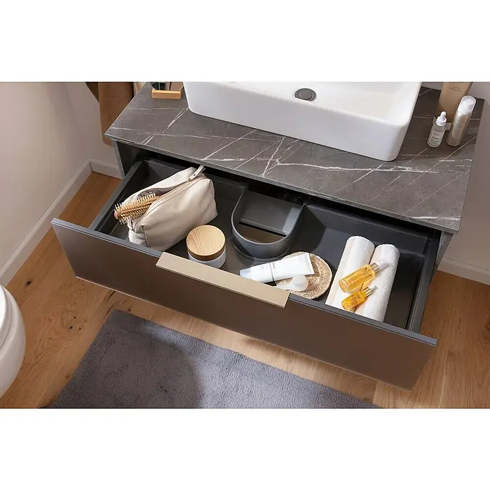 Camargue Marble Badmöbel-Set - 90 cm, Grau Marmor/Goldbronze, 3 -tlg. - Das Bild zeigt einen offenen Badezimmerschrank mit verschiedenen Pflegeprodukten wie Handtüchern, Cremes und einer Kosmetiktasche.