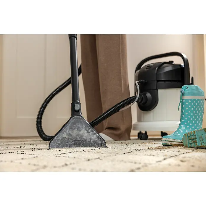 Kärcher Waschsauger SE 4 - 1.000 W, Behältervolumen: 4 l - Ein Kärcher-Reiniger in Aktion auf einem Teppich, daneben ein türkisfarbener Gummistiefel. Ideal für die effektive Reinigung.