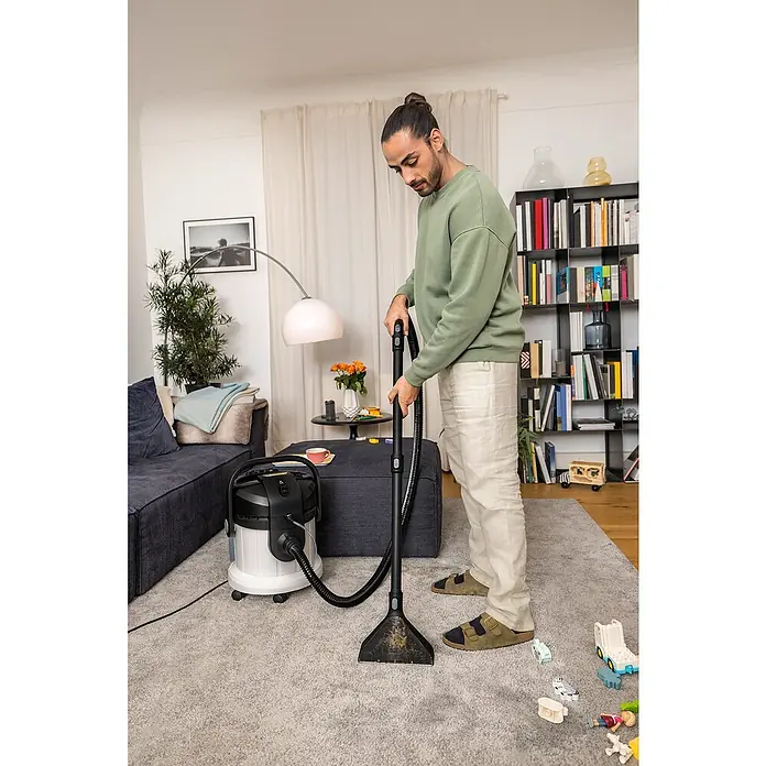 Kärcher Lava-aspirador SE 4 - 1.000 W, Volumen de recipiente: 4 l - Un hombre usa un limpiador de alfombras Kärcher, limpiando eficazmente la alfombra. Perfecto para hogares con niños y mascotas.