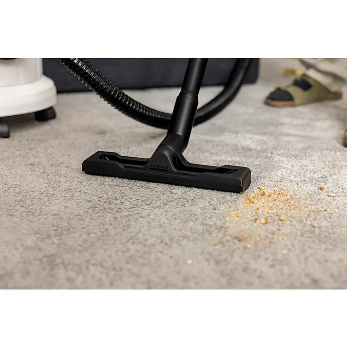 Kärcher Waschsauger SE 4 - 1.000 W, Behältervolumen: 4 l - Detailaufnahme des Kärcher Staubsaugers beim Reinigen von Krümeln auf einem Teppich.