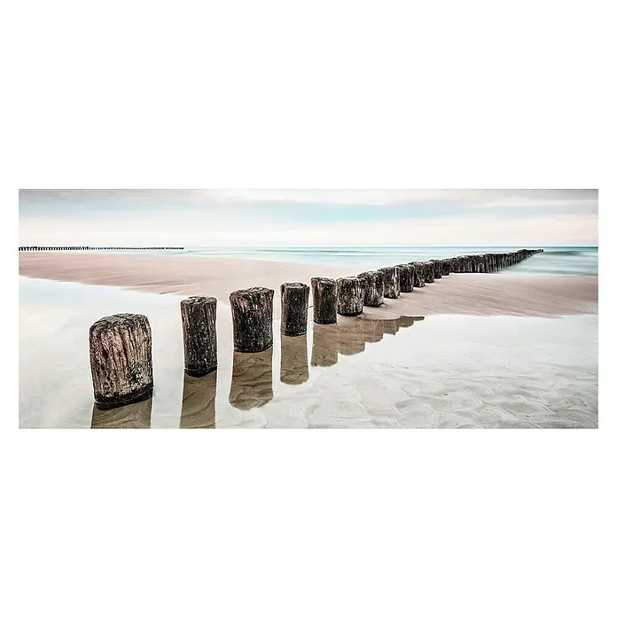 Glasbild - Strand, B x H: 125 x 50 cm - Lange Reihe von Holzpfosten am Strand, die sich im Wasser spiegeln, unter einem ruhigen, bedeckten Himmel.