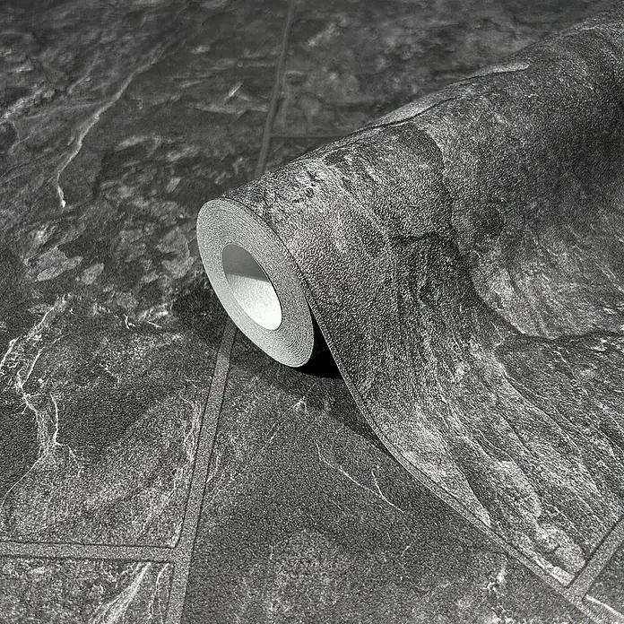 Marburg Struktura Vliestapete - Anthrazit, Fliesenoptik, 10,05 x 0,53 m - Nahaufnahme einer Rolle grauer Mauerwerk-Tapete, die die Textur und das Muster des Produkts hervorhebt. Ideal für moderne Innenräume.