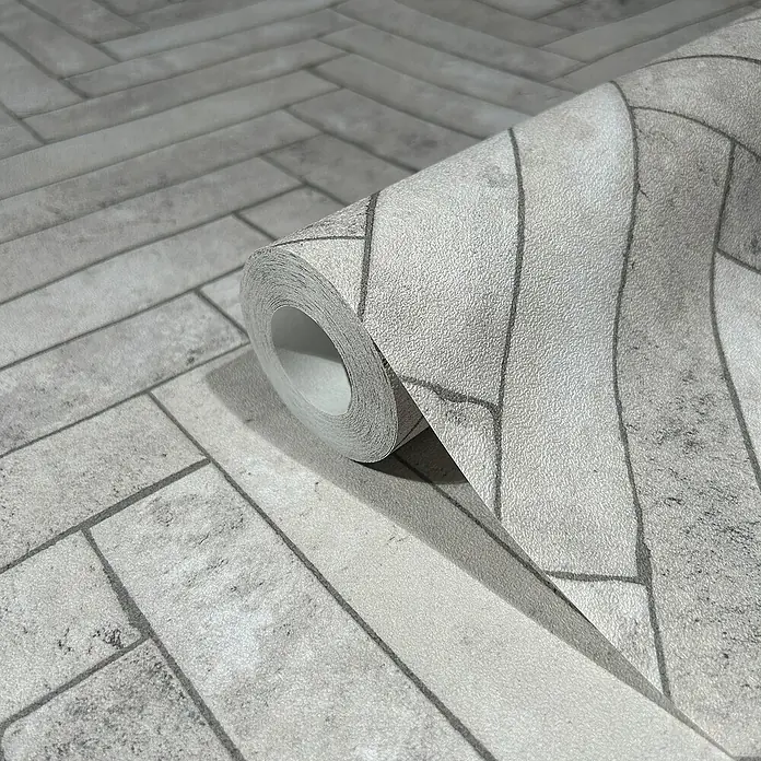 Marburg Struktura Vliestapete Fischgrat - Grau, Steinoptik, 10,05 x 0,53 m - Nahaufnahme einer Rolle grauer Ziegelmuster-Tapete, die ein realistisches und stilvolles Aussehen für die Inneneinrichtung bietet.