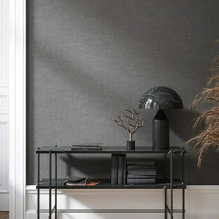 Marburg Struktura Vliestapete Struktur - Anthrazitgrau, Uni, 10,05 x 0,53 m - Elegante Konsole mit Marmorplatte, darauf eine moderne Lampe und dekorative Bücher, die dem Raum einen stilvollen Akzent verleihen.