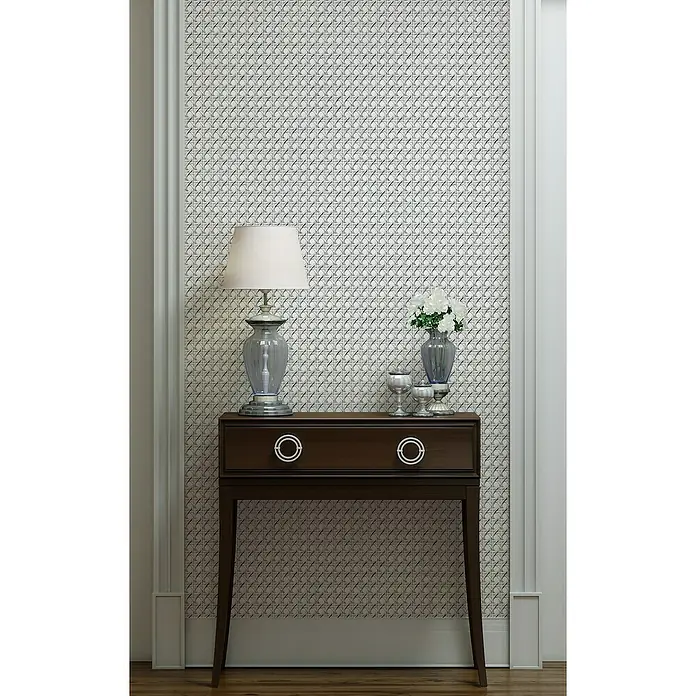 Marburg Struktura Vliestapete Holzgeflecht - Weiß/Grau, Holzoptik, 10,05 x 0,53 m - Elegantes Interieur mit dunklem Holzschrank, Lampe und Blumenvase vor einer stilvollen gemusterten Tapete, die dem Raum Charakter verleiht.