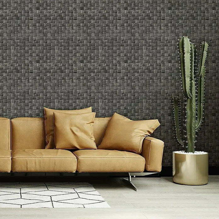 Marburg Struktura Vliestapete 3D-Geflecht - Anthrazit, 3D-Optik, 10,05 x 0,53 m - Elegantes Interieur mit braunem Ledersofa, Kissen, Kaktus im goldenen Topf und einem geometrischen Teppich vor einer stilvollen Mosaikwand.