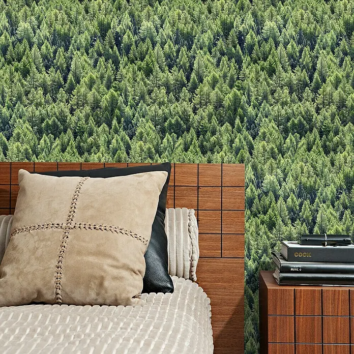 Marburg Struktura Vliestapete Nadelwald - Grün, Floral, 10,05 x 0,53 m - Elegantes Schlafzimmer mit Holzbett, hellen Kissen und Nachttisch mit Büchern vor einer Waldtapete.