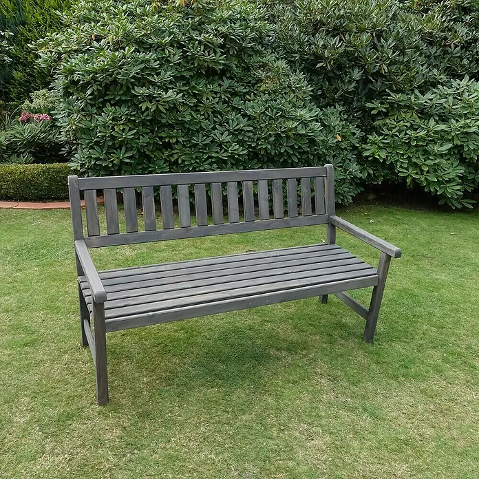 Promadino Gartenbank Johanna - B x T x H: 154 x 71 x 88,5 cm, Kiefer, Grau - Eine graue Gartenbank mit Lattenrost steht auf einer Rasenfläche vor einem grünen Busch. Die Bank lädt zum Verweilen im Garten ein.